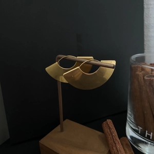 Detail of gold fan-shaped geometric earrings hanging on a dark wood display stand