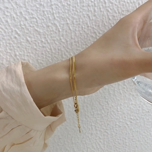 Detail of a layered gold snake chain bracelet with adjustable lobster clasp on wrist