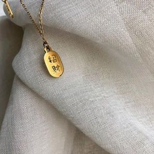 Collier minimaliste en or 18 carats avec gravure Zhaocai sur fond de lin blanc