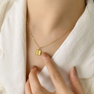Collier minimaliste en acier titane doré avec pendentif carré rose porté par mannequin