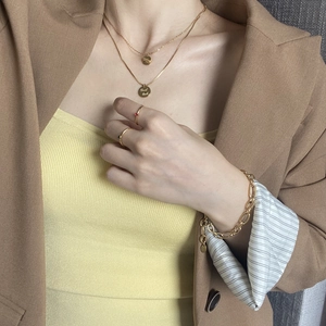 Close-up of golden Good Luck pendant necklace with stacking rings and chain bracelet set