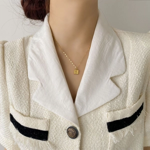 Détail d'un collier en titane doré avec pendentif rose carré sur un mannequin