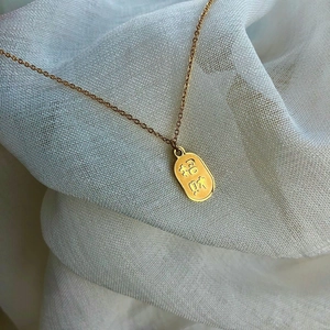 Gros plan d'un pendentif ovale doré avec gravure de chance sur chaîne fine