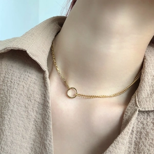Detail of gold asymmetric necklace with mixed box and bead chains and ring pendant