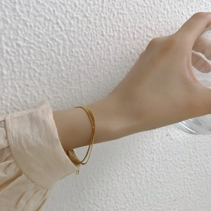 Close-up of minimalist gold double-layer snake chain bracelet on model wrist