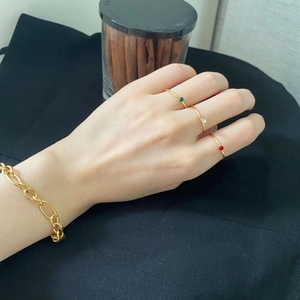 Detail of 14k gold plated ring set with green and red zircon stones on a model's hand