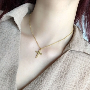Minimalist gold cross necklace with engraved pendant shown on model for a trendy look