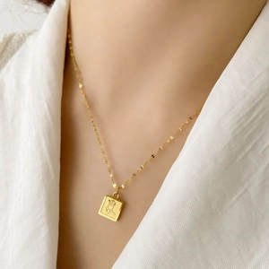 Gros plan du pendentif carré doré avec une rose en relief sur de l'acier au titane