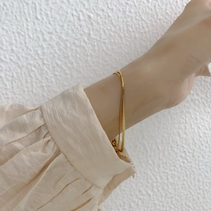 Elegant gold double-layer snake and curb chain bracelet for women on a model wrist