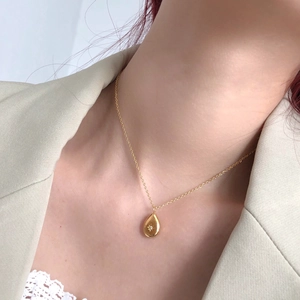 Close-up of golden teardrop necklace with starburst detail on a model neck