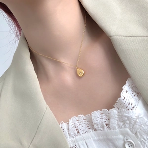 Detail of gold titanium steel teardrop pendant necklace with starburst engraving on model
