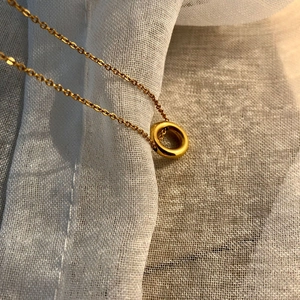 Collier élégant doré avec pendentif cercle géométrique sur tissu blanc doux
