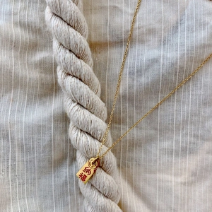 Macro shot of gold-plated square pendant necklace with Chinese characters and coin symbols