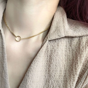 Detail of a gold double-layer necklace with box chain, bead chain and circular pendant