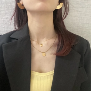 Detail of gold layered necklaces with circular pendants and half-round hoop earrings