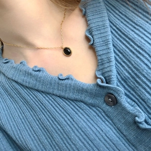Close-up of vintage oval black agate pendant on a gold chain worn by a female model