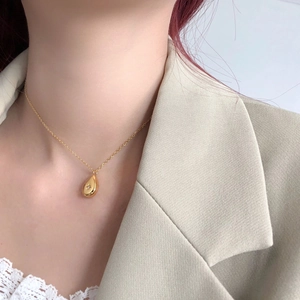 Detailed close-up of a gold water-drop pendant necklace with a tiny starburst engraving