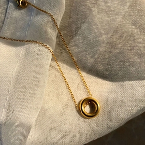 Collier à pendentif cercle géométrique minimaliste doré sur fond de tissu blanc texturé