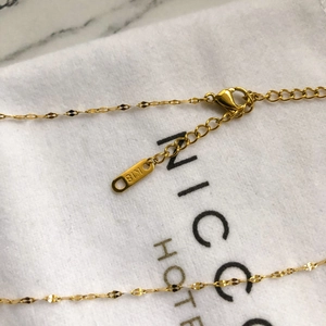 Détail du collier en or montrant le poinçon K18, le fermoir mousqueton et la chaînette