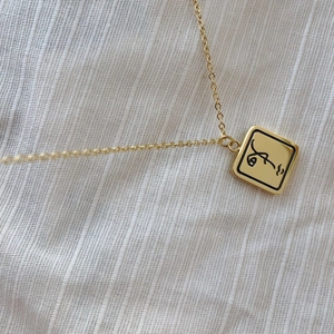 Collier minimaliste en or avec pendentif carré et gravure de visage abstrait moderne