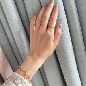 Detail of minimalist gold-plated rings with red and white gemstones and chain bracelet