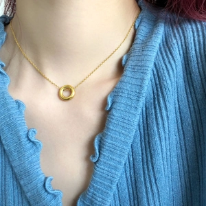 Gros plan du collier géométrique doré avec pendentif cercle sur un pull bleu
