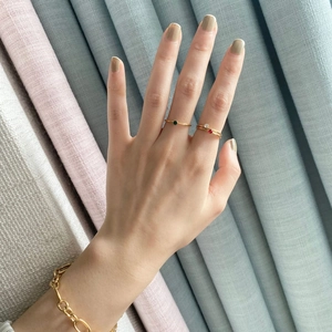 Three minimalist 14k gold-plated rings with green and red gems paired with a chain bracelet