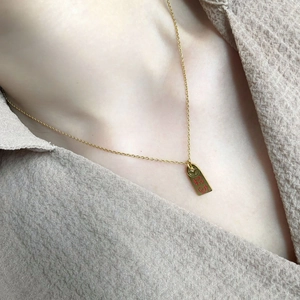 Detail of gold rectangular pendant with Chinese characters and coin pattern on necklace