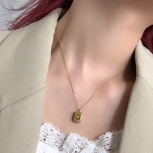 Close-up of golden rectangular titanium pendant with starburst engraving on model