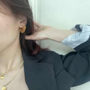 Close-up of matte gold geometric semi-circle earrings and layered necklaces on a model