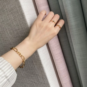 Close-up of minimalist 14k gold chain bracelet and rings with ruby and emerald gems