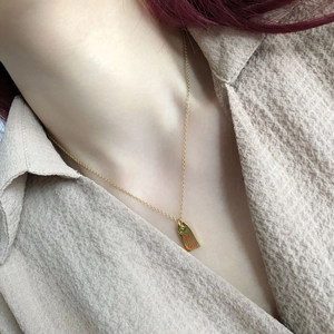 Detail of a gold-plated rectangular coin pendant with red 'Fortune' engraving on neck