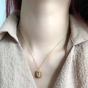 Gros plan d'un collier doré minimaliste avec gravure de visage abstrait sur un mannequin