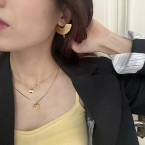Close-up of double-layer gold necklace with circular Good Luck pendants and fan earrings