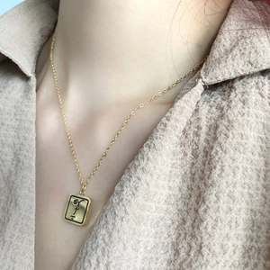 Collier doré minimaliste avec gravure de visage abstrait sur un pendentif rectangulaire