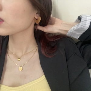 Golden double-layer necklace with round pendant and fan-shaped earrings on a model