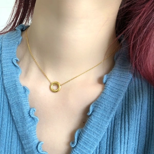 Collier minimaliste à pendentif cercle doré porté par un mannequin en tricot bleu