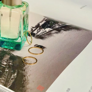 Set of three minimalist gold thin rings arranged on an artistic magazine background