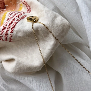 Gros plan du pendentif rond doré avec gravure de visage artistique sur fond en tissu rustique