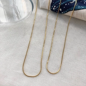 Vue détaillée de trois colliers en maille serpent dorée à texture lisse polie