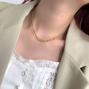 Detailed close-up of a three-layer gold beaded choker necklace worn with a suit jacket