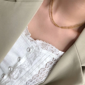 Close-up of golden three-layer satellite chain necklace with delicate beads on model
