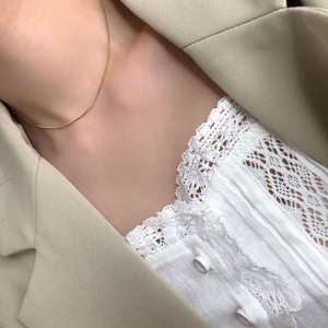 Collier chaîne serpent doré minimaliste porté avec un blazer pour un look chic