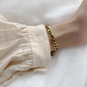 Chic bracelet gourmette en titane plaqué or 18 carats porté au poignet d'une femme