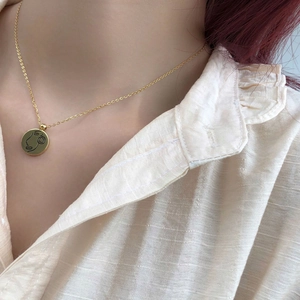 Collier minimaliste en or avec pendentif rond gravé d'un visage au trait fin