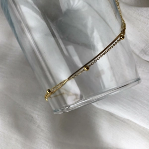 Détail d'un bracelet doré double couche avec chaîne serpent et perles délicates sur verre