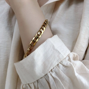 Gros plan d'un bracelet gourmette doré au poignet avec fermoir mousqueton ajustable