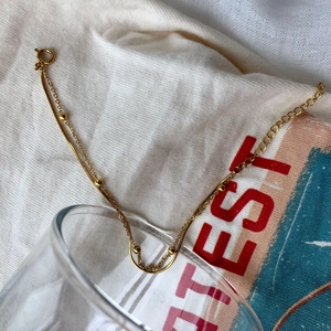 Détail d'un bracelet double couche doré minimaliste avec chaîne serpent et petites billes