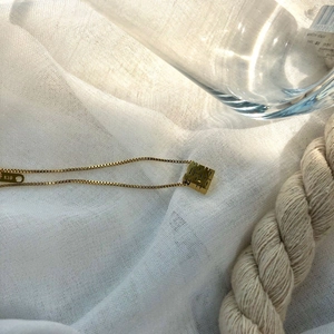 Detailed close-up of 18K gold necklace showing K18 hallmark and hollow Xi character pendant