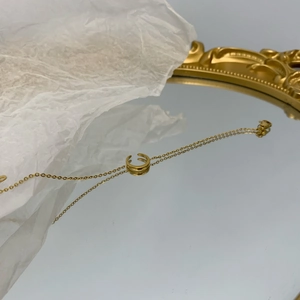 Dettaglio della collana a mezzaluna d'oro su specchio vintage con riflessi eleganti